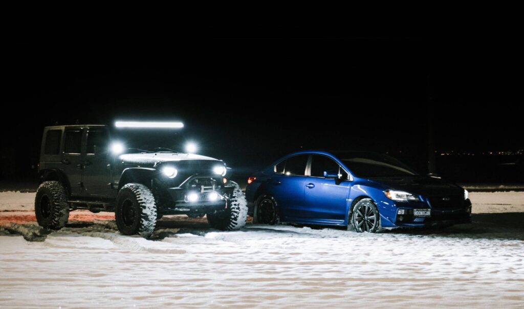 subaru wrx with bright headlights next to a jeep with a lightbar