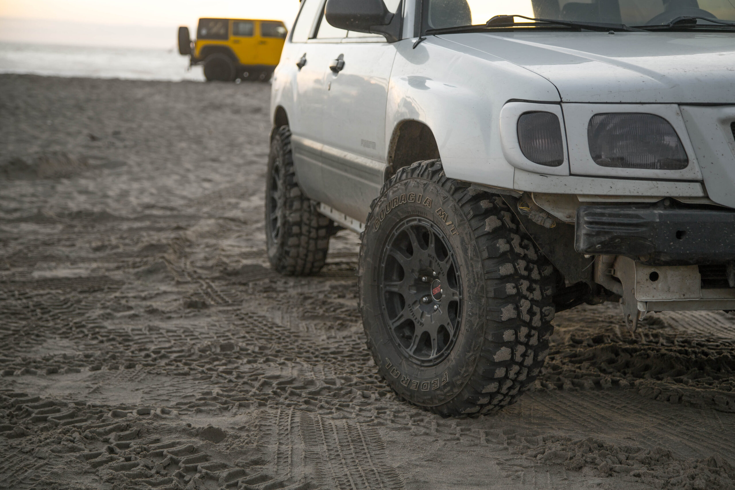 lifted subaru forester on the beach driving in the sand with Mud tires