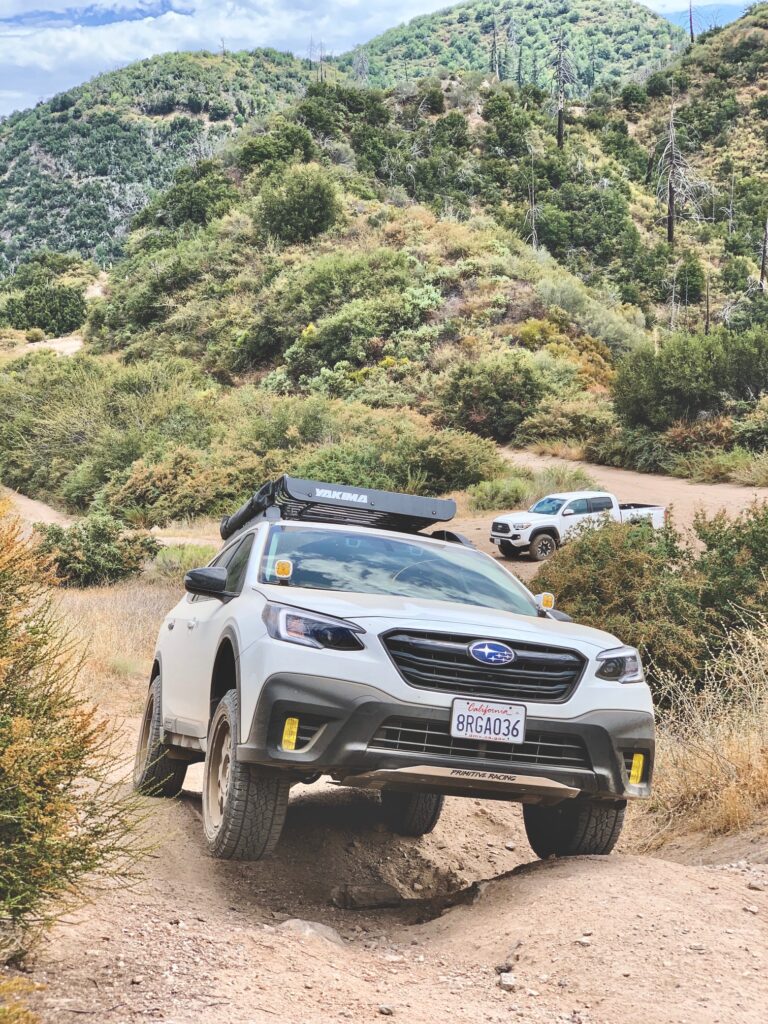 lifted 2020 subaru outback xt with off road tires climbing a hill