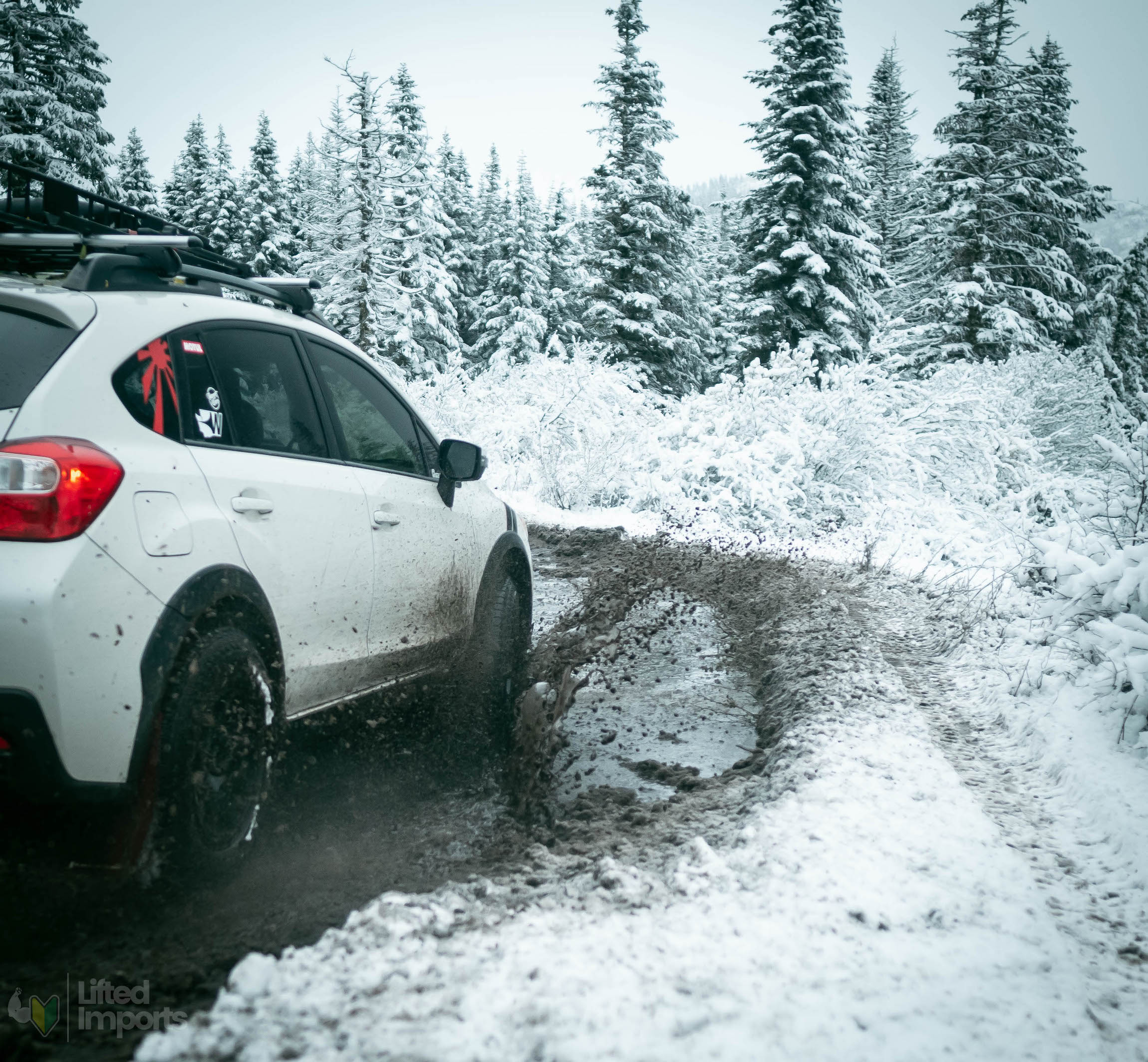 white lifted subaru crosstrek with offroad tires and method mr502 wheels in the snow going through mud