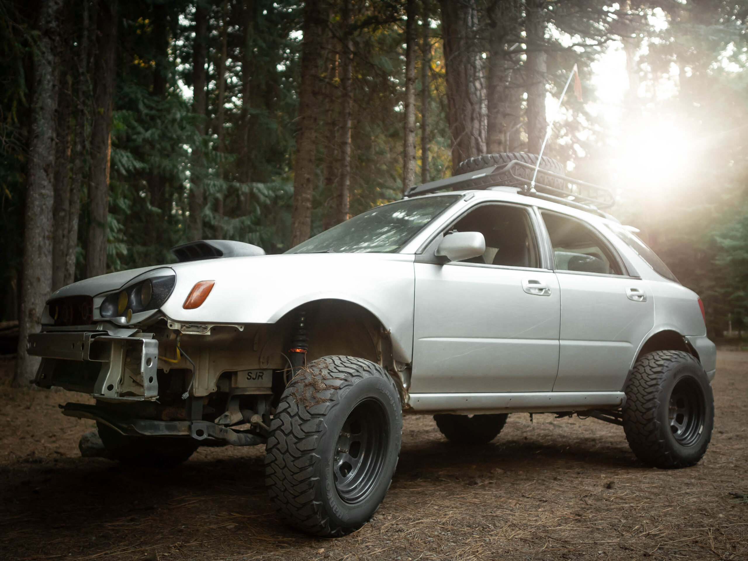 lifted subaru wrx offroad in the forest with Morette headlights and sunset